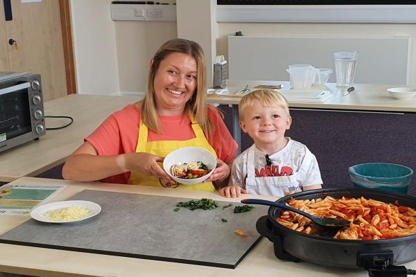 Lady and small child showing Healthy pasta dish they have cooked